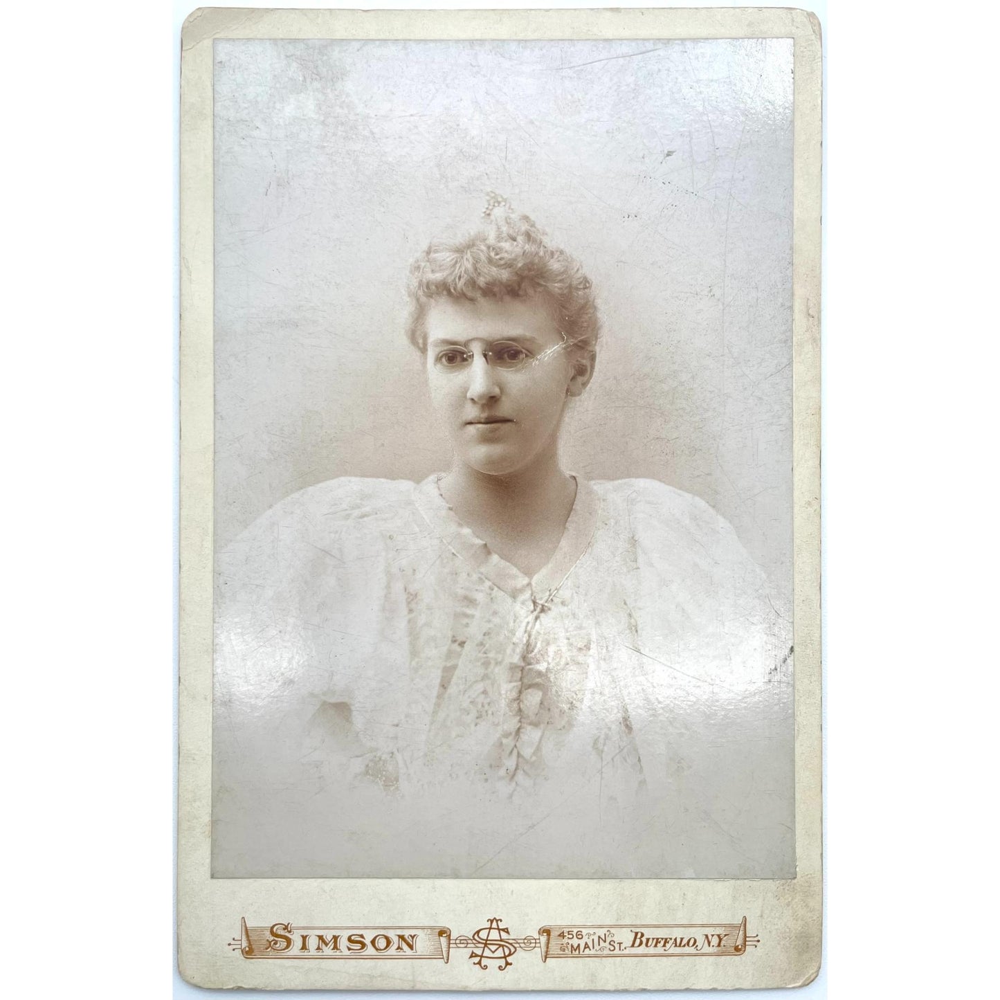 [Cabinet card of young woman in a dress wearing glasses in Buffalo, New York]